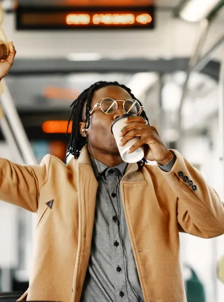 Homme tenant une poignée et buvant un café dans un autobus - Man holding a handle and drinking coffee on a bus